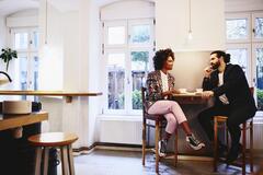 Woman and man sitting at a table with coffee. Having a conversation.