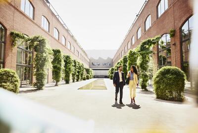 Man and woman walking outside between office buildings.