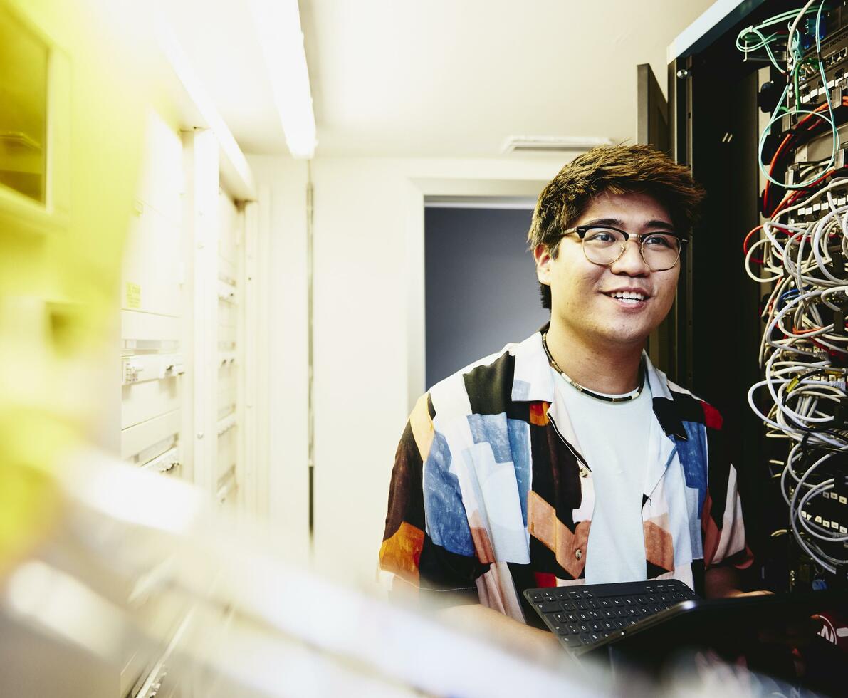 Smiling man holding an tablet standing in a servers room.