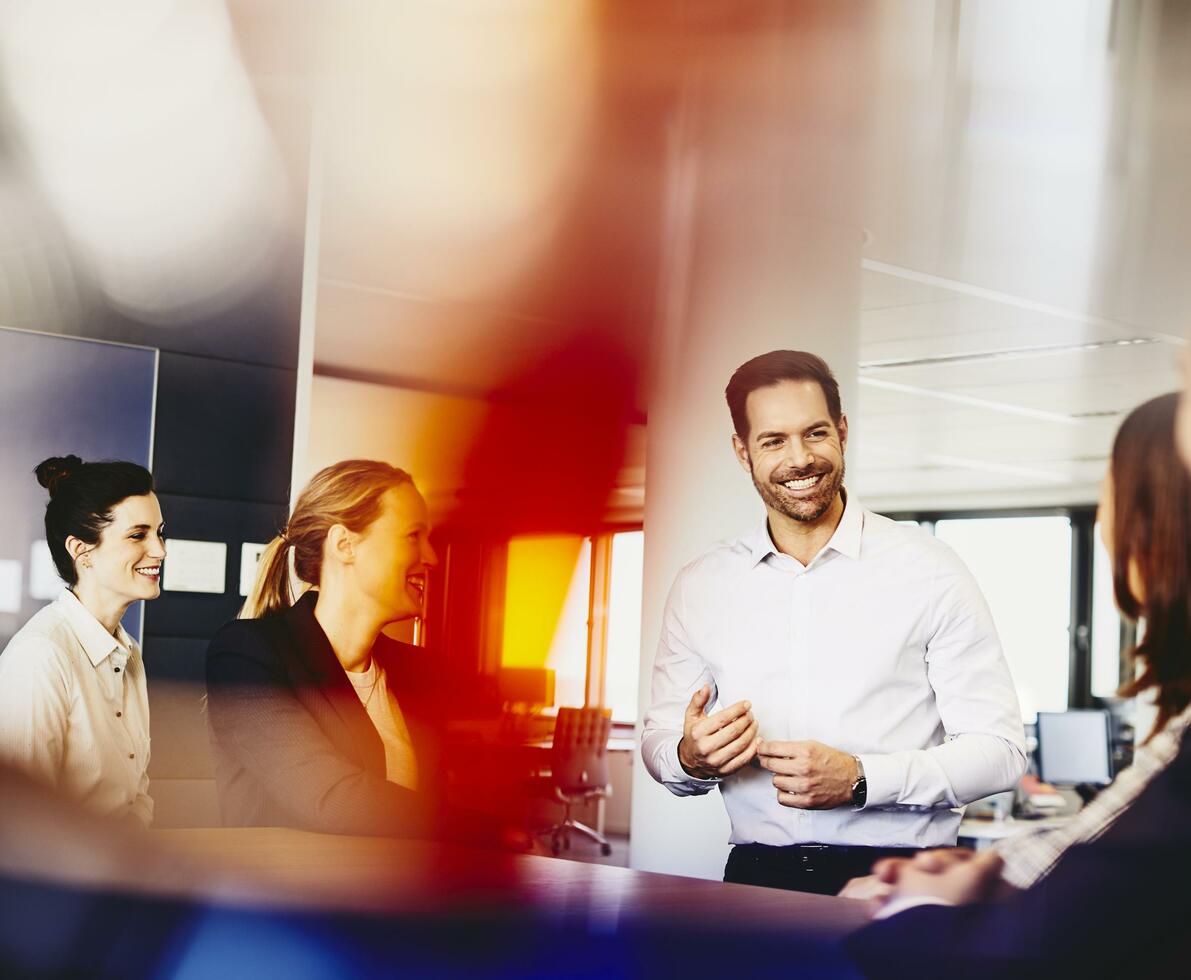 Business men and women in an office having a meeting. Primary color: red. Business men and women in an office having a meeting. Primary color: red.