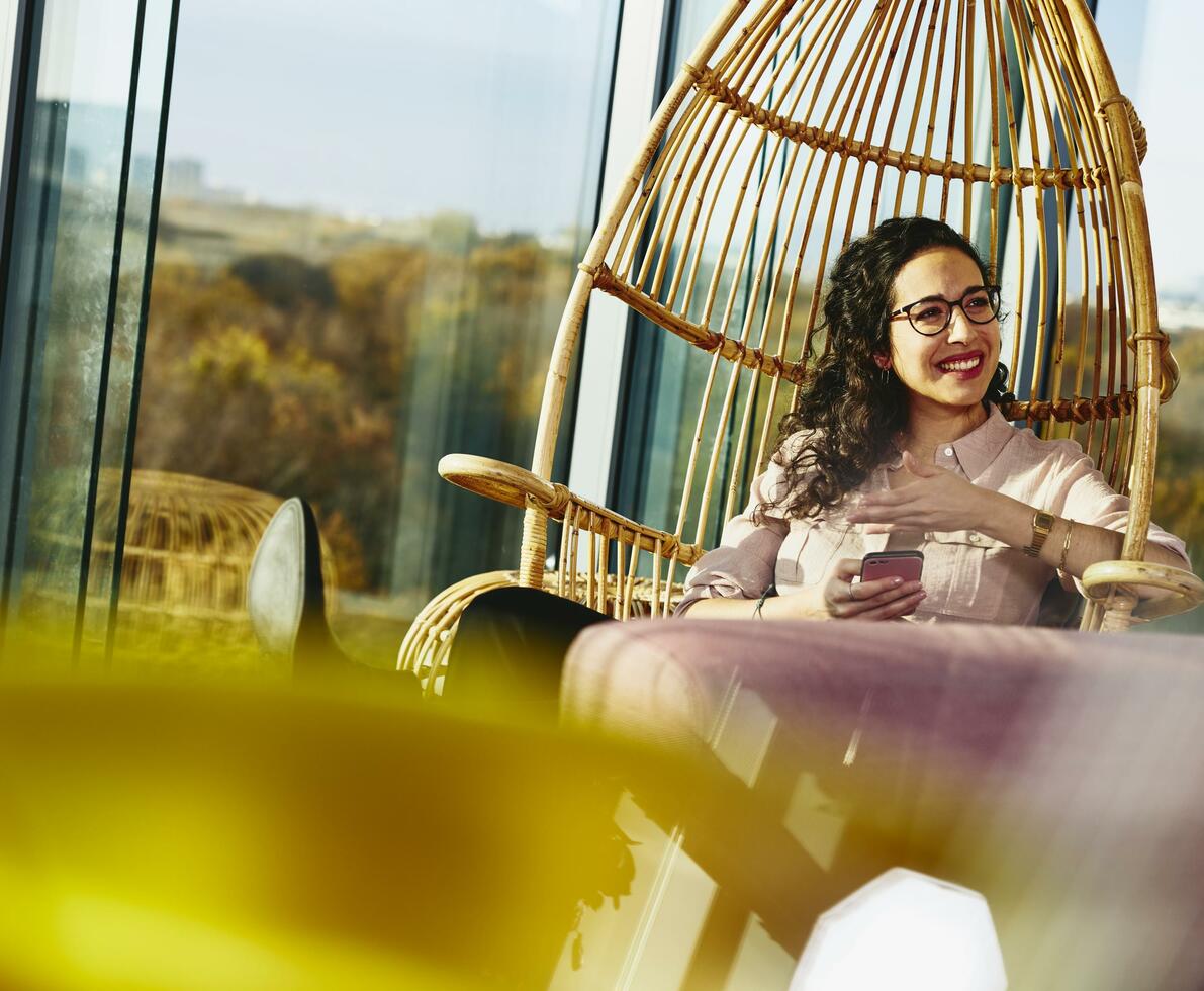 Woman smiling looking away while sitting down and holding her phone. Woman smiling looking away while sitting down and holding her phone.