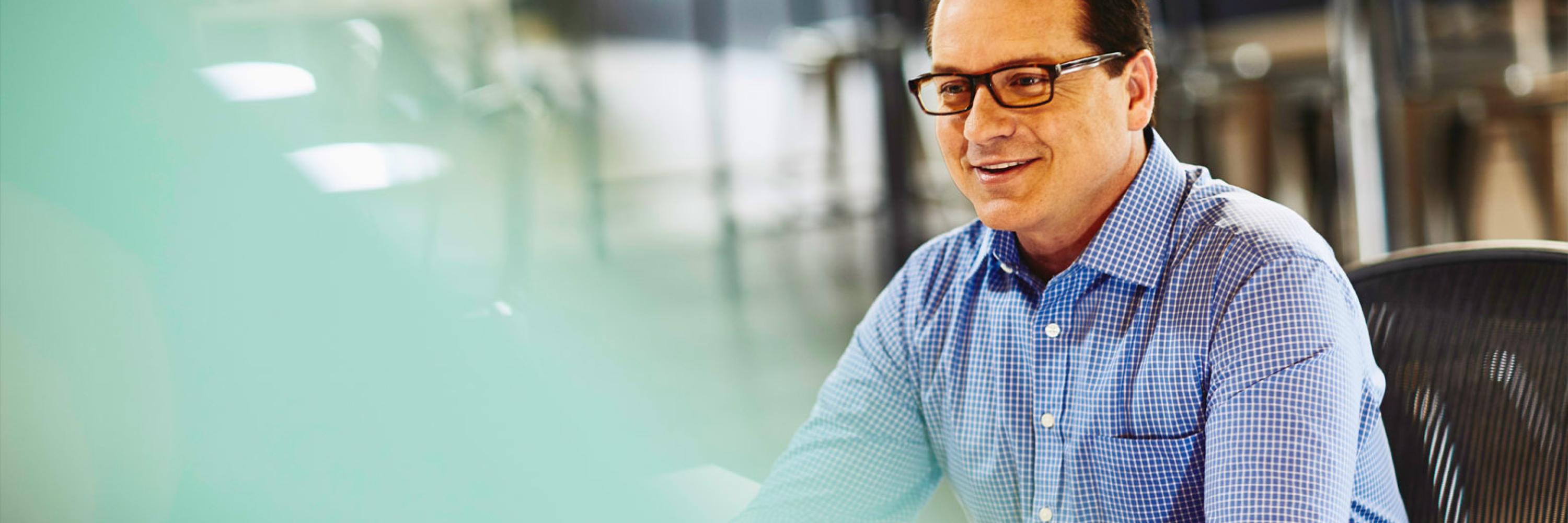 white male sitting at desk smiling